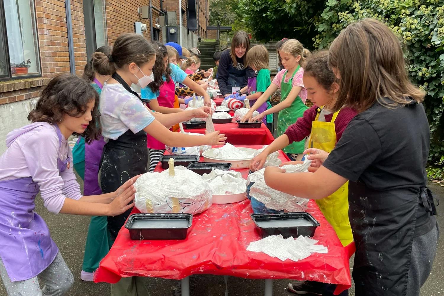 Children making papier-mâché sculptures on a table