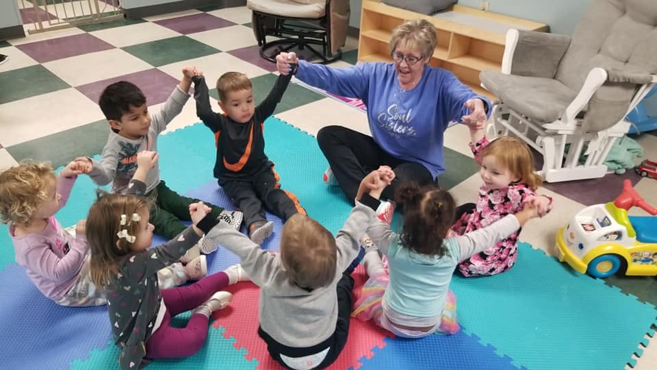 Adult and children sitting in a circle holding hands