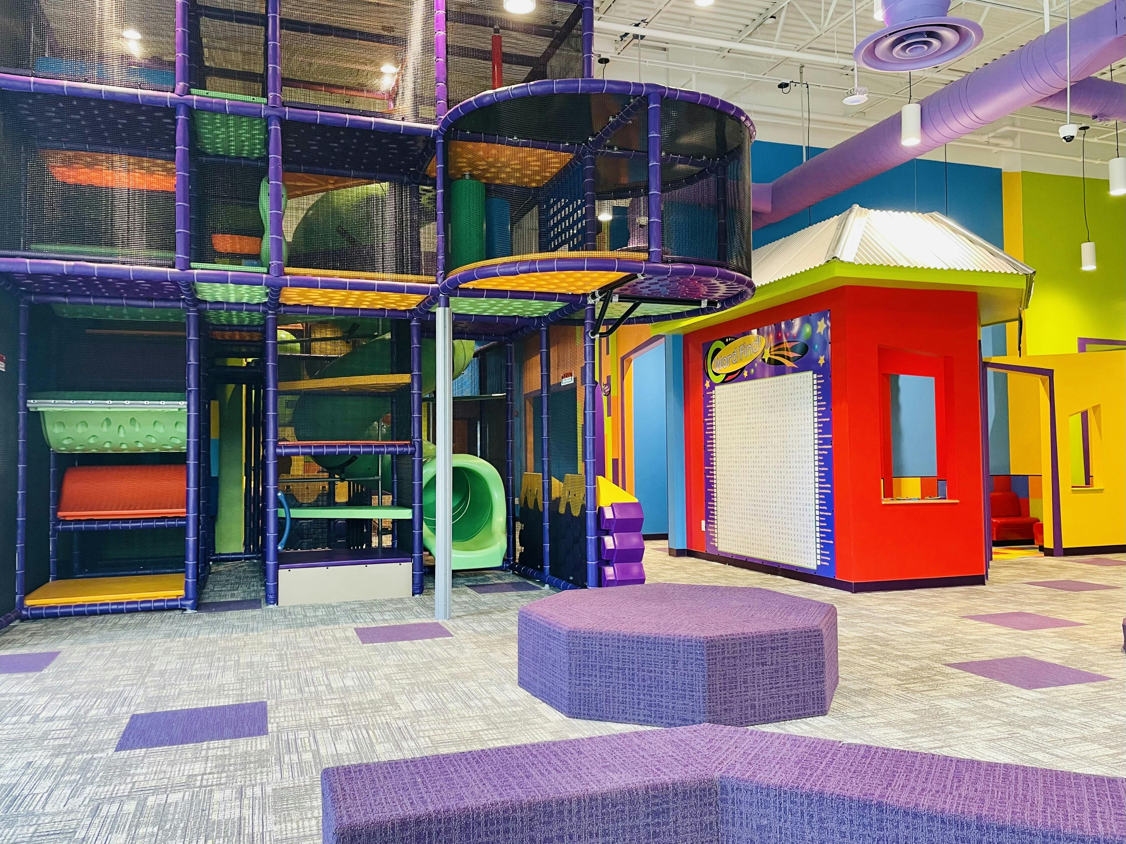 Indoor playground with multi-level climbing structure and playhouse
