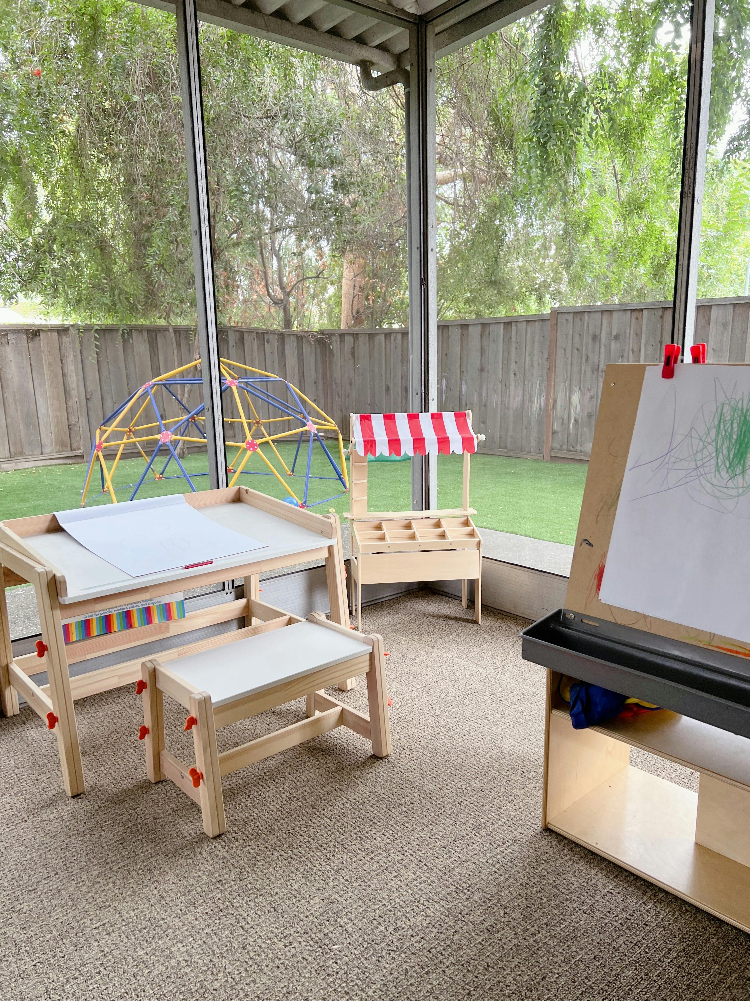 Children's art table, easel, and play market stand on a screened porch