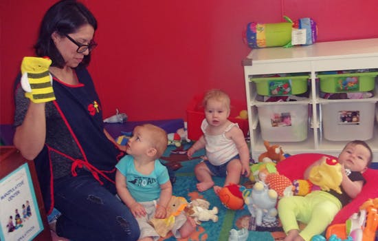 Person holding a bee puppet with three babies on the floor