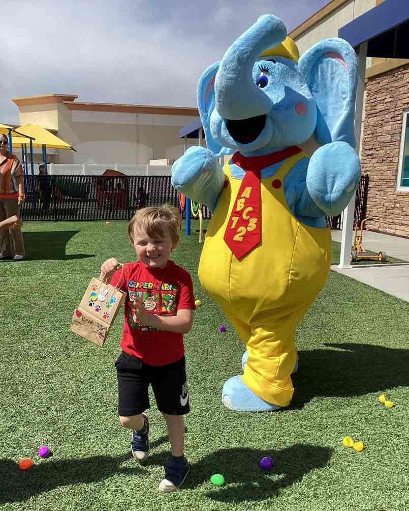 Child holding a bag next to a person in an elephant costume