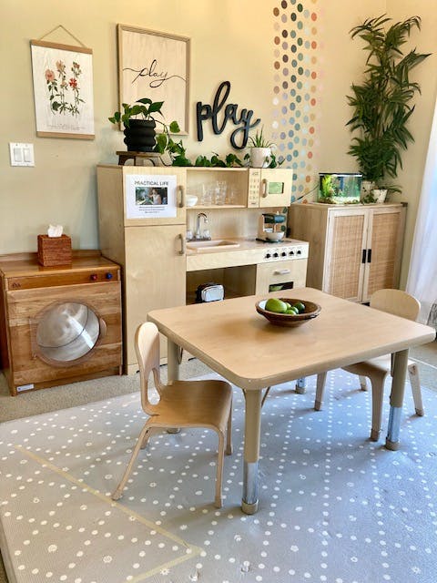 Children's play kitchen and table with chairs in a room