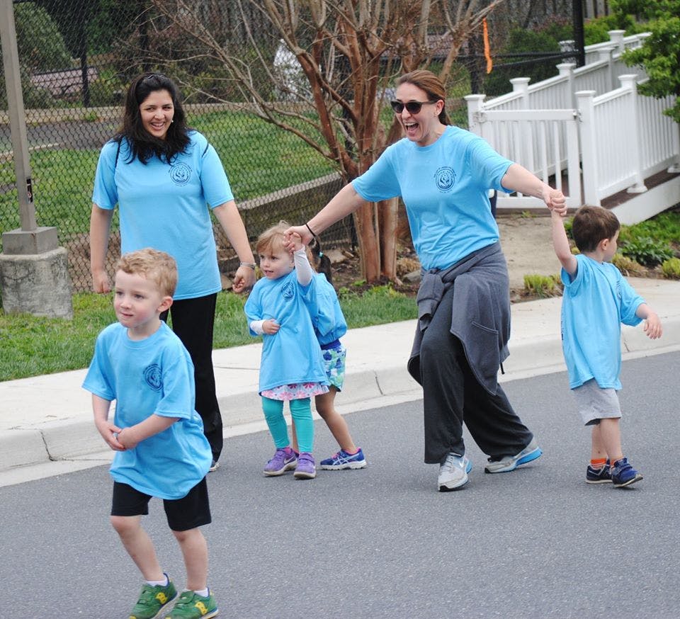 Two adults and three children walking on a paved surface