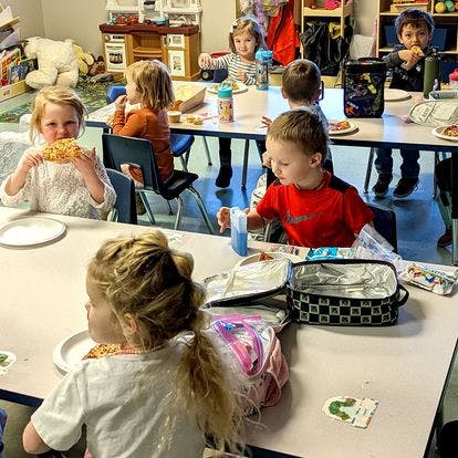 Children eating lunch at tables in a classroom