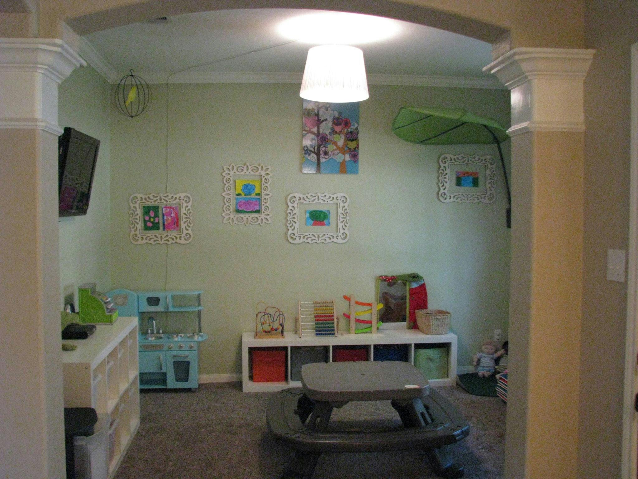 Playroom with children's artwork on walls, toy kitchen, and storage cubbies