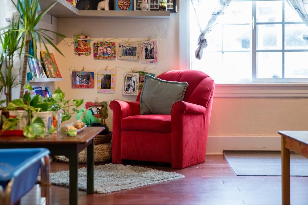 Red armchair with a pillow in a room with a window and plants