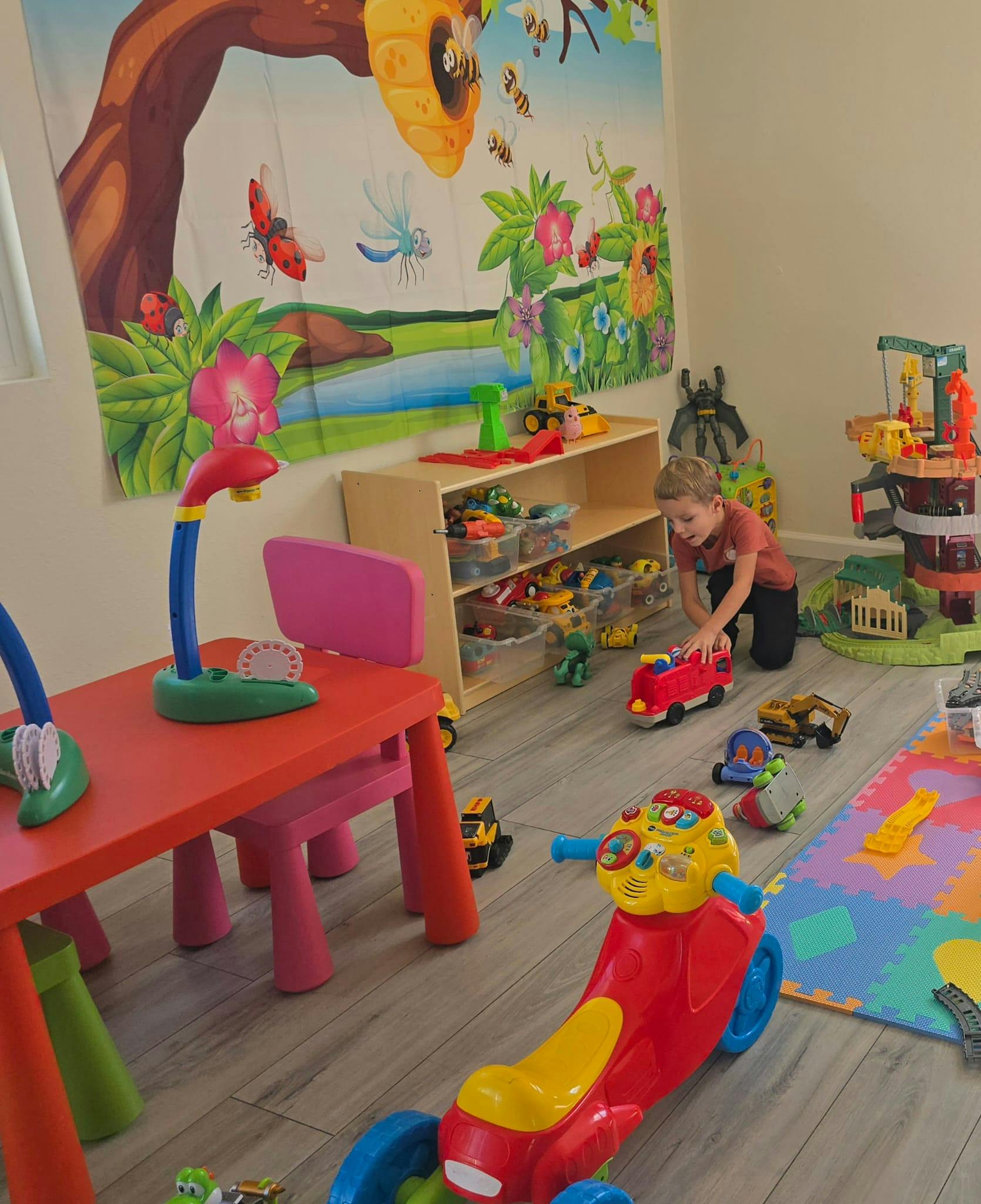 Child playing with a toy fire truck in a playroom