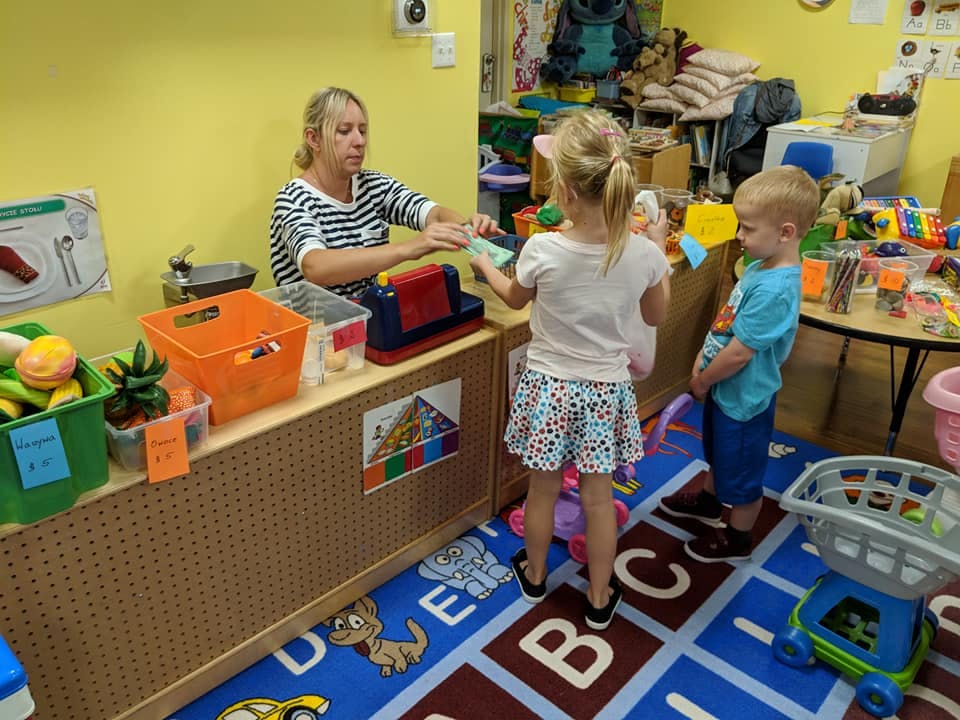 Adult and two children playing in a classroom