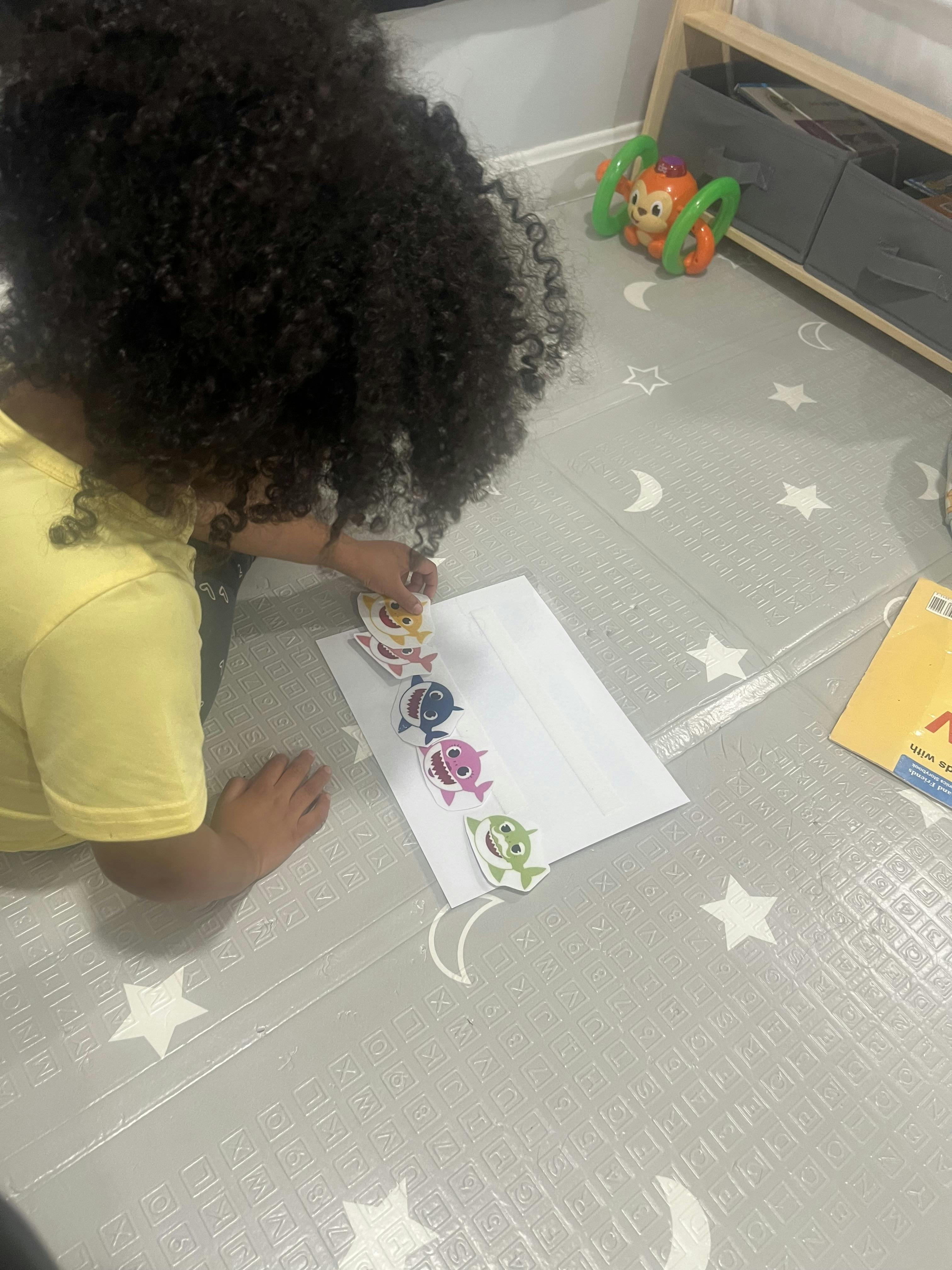Child putting shark stickers on a piece of paper