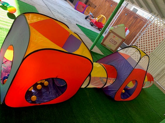Colorful play tunnel and tent on green turf