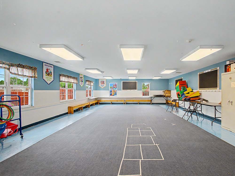 Empty activity room with blue and white walls, benches, and a hopscotch outline
