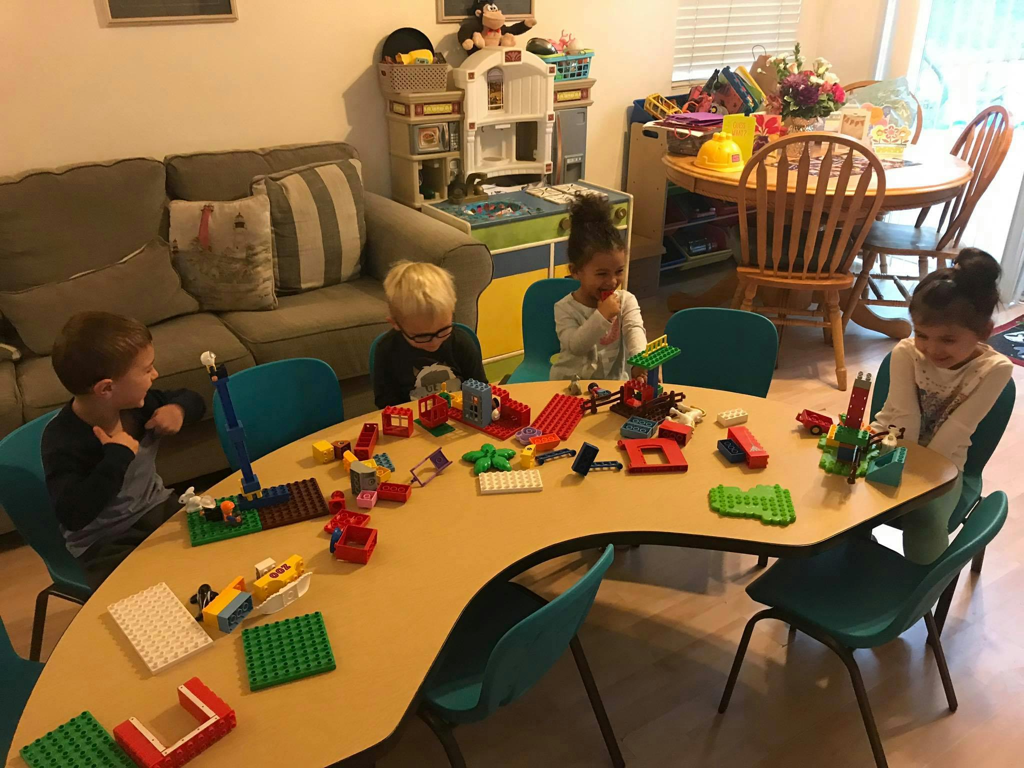 Four children playing with building blocks at a curved table