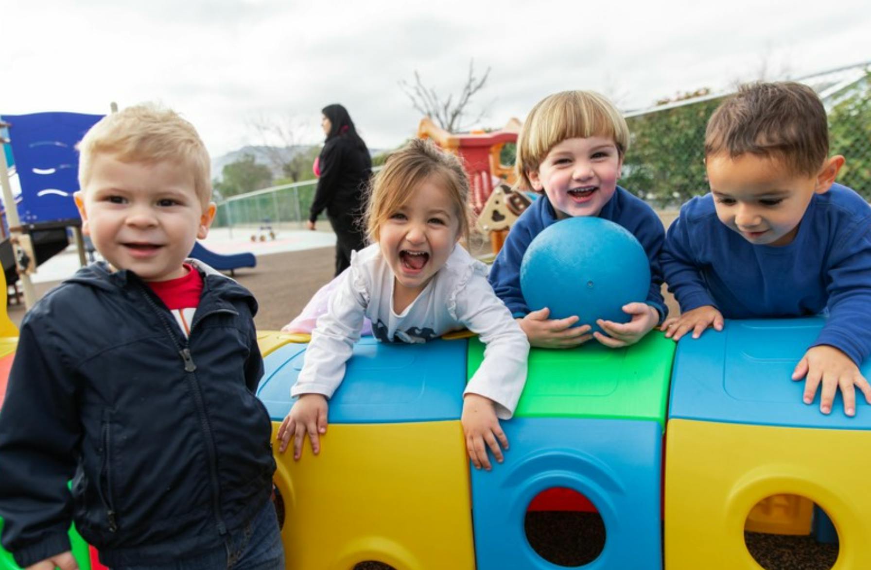 Four children playing on a colorful climbing toy at a playground