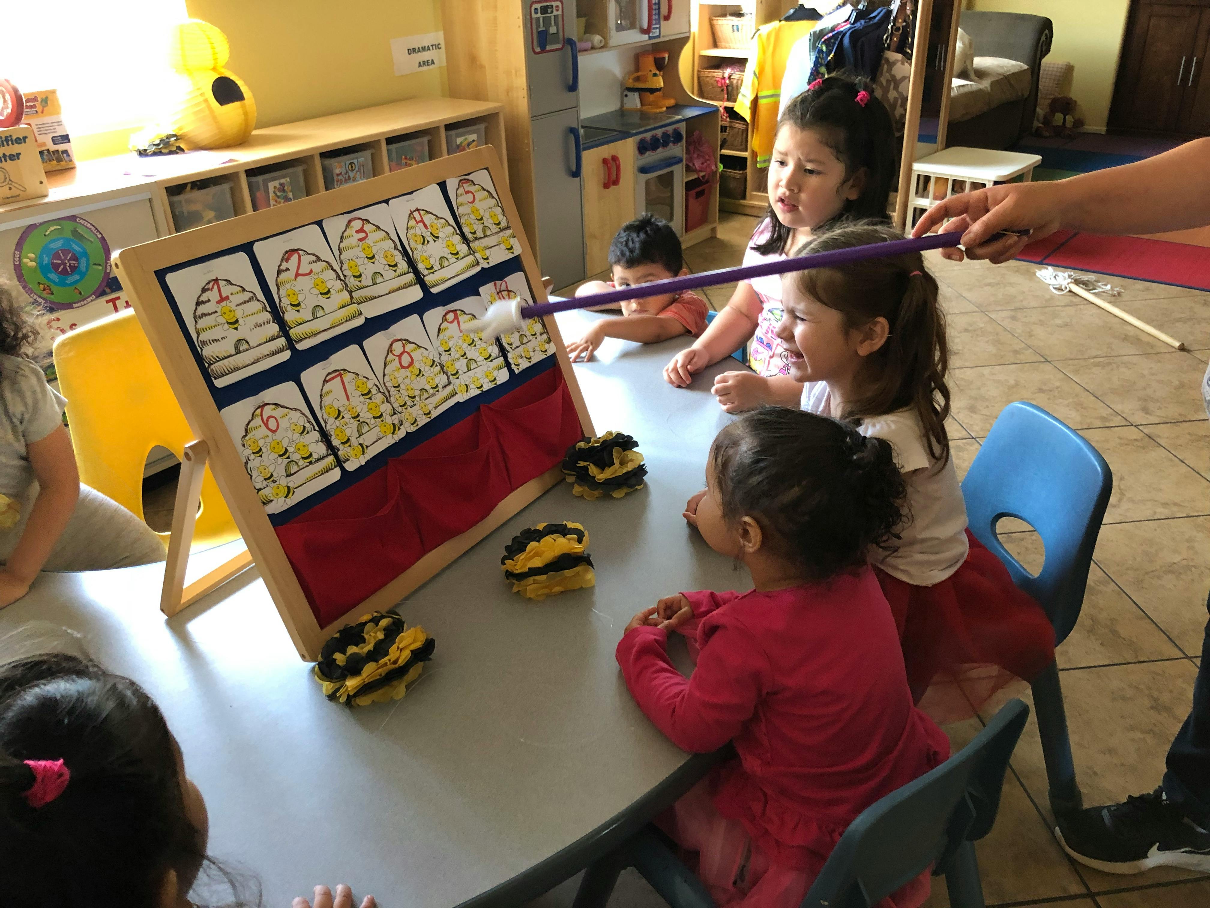 Children in a classroom looking at a display board with a pointer