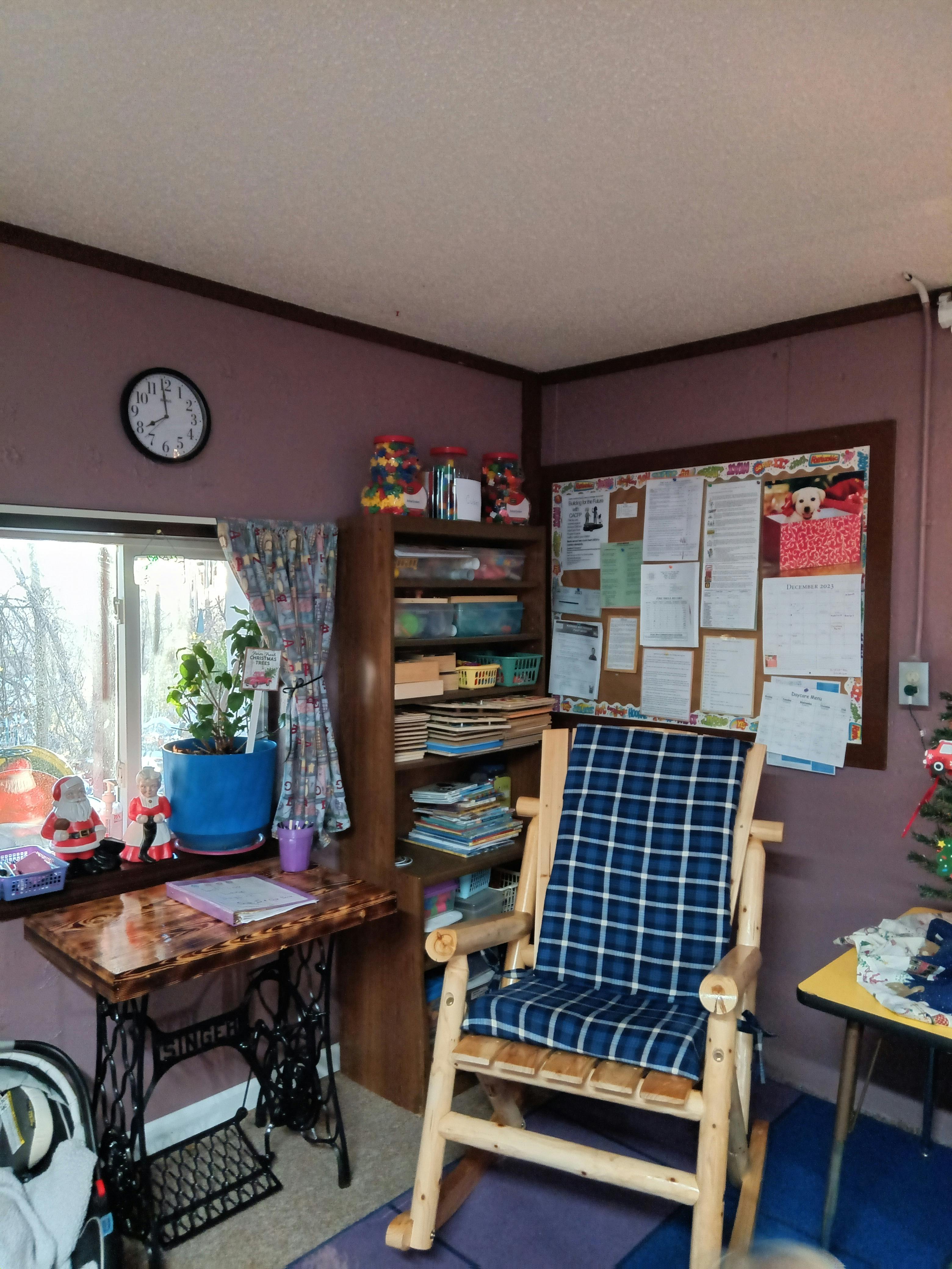 Room with a wooden rocking chair, a desk, and a bulletin board