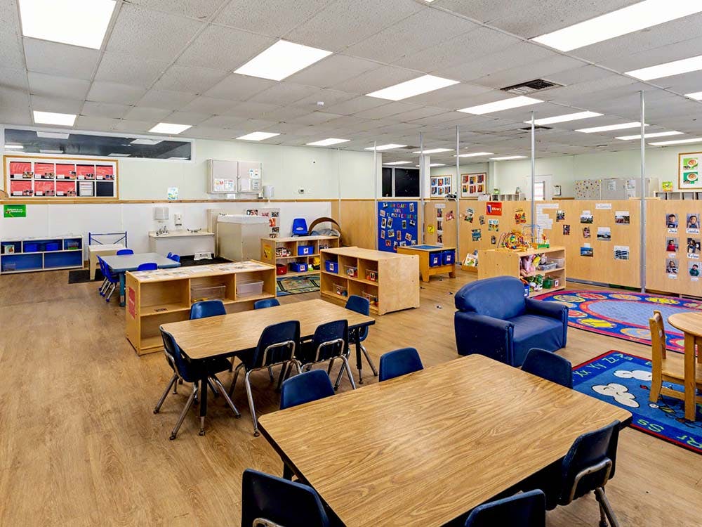 Classroom with tables, chairs, bookshelves, and divider walls