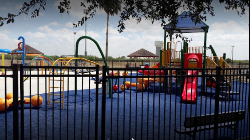 Playground with slides and climbing structures behind a black fence