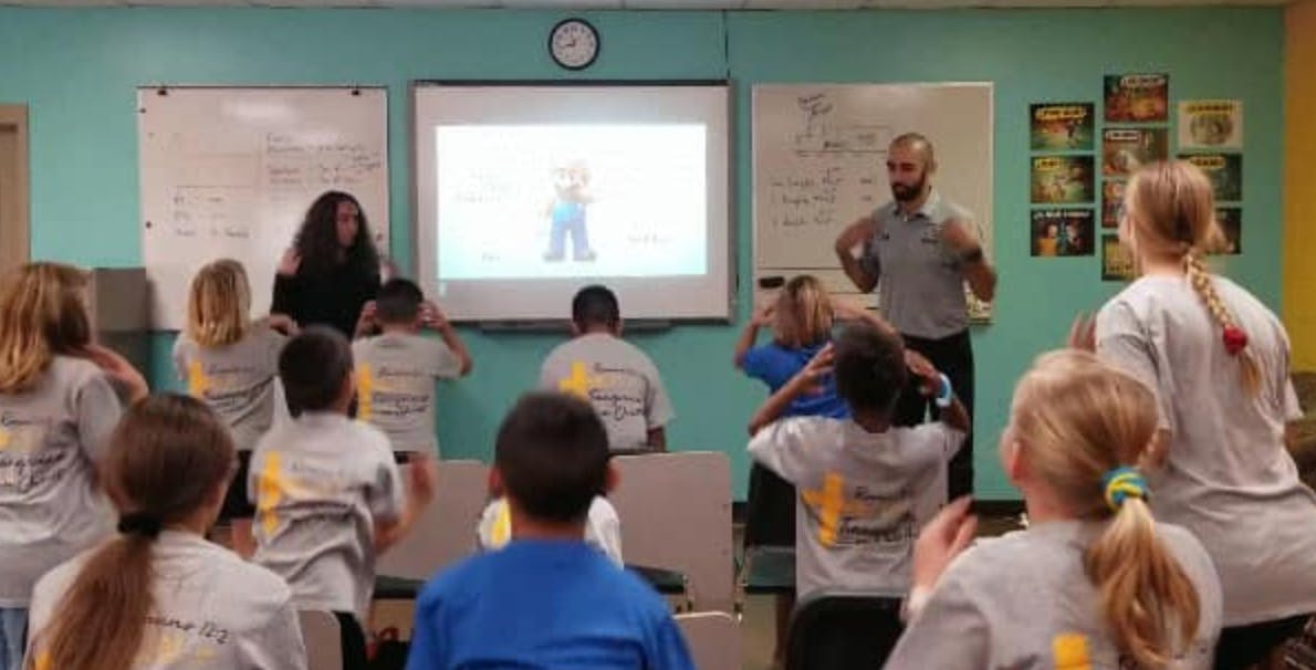 Adults leading a group of children in an activity in a classroom