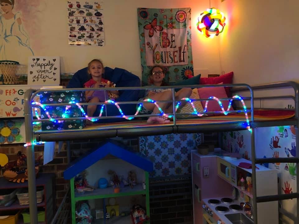 Two people on a bunk bed decorated with string lights
