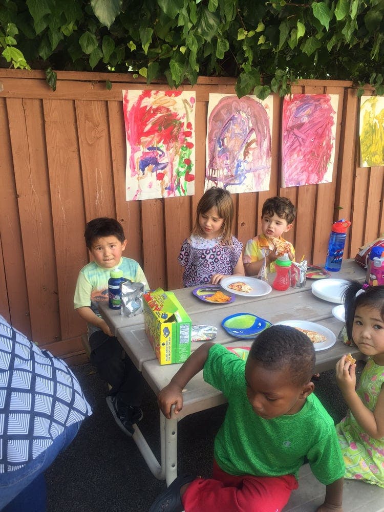 Children sitting at a picnic table with plates of food