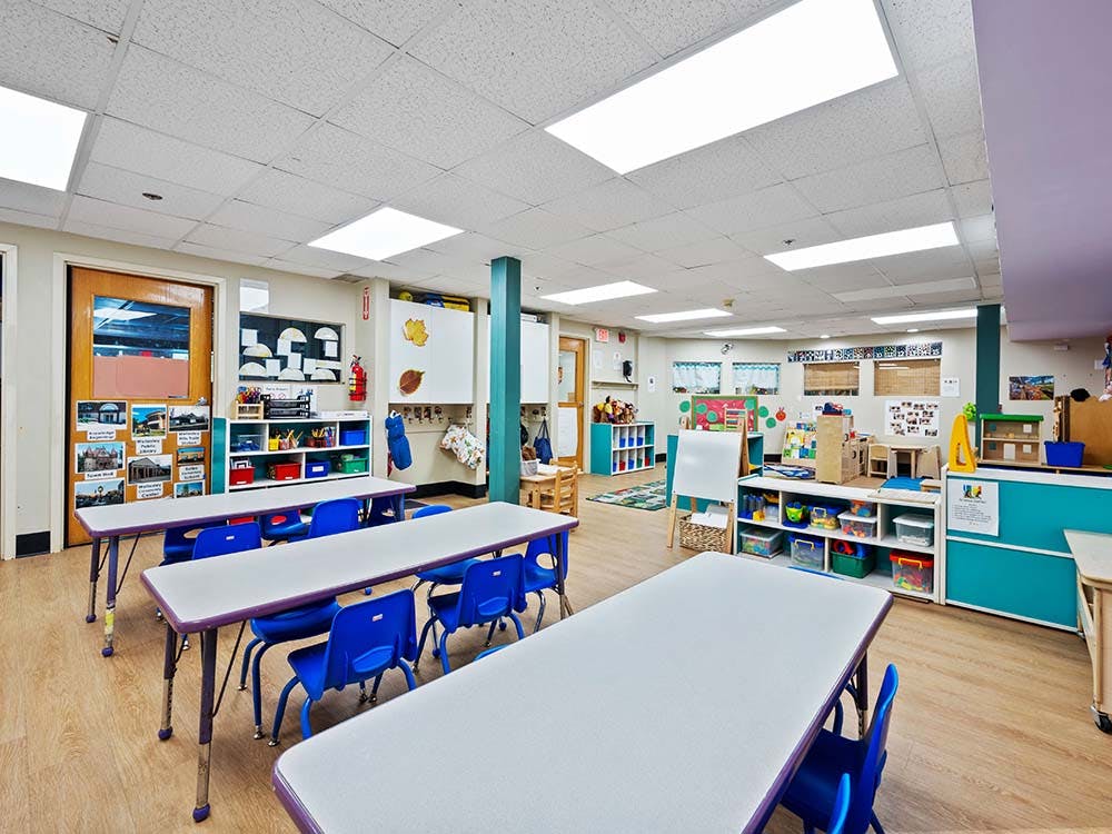 Empty colorful preschool classroom with small tables and chairs
