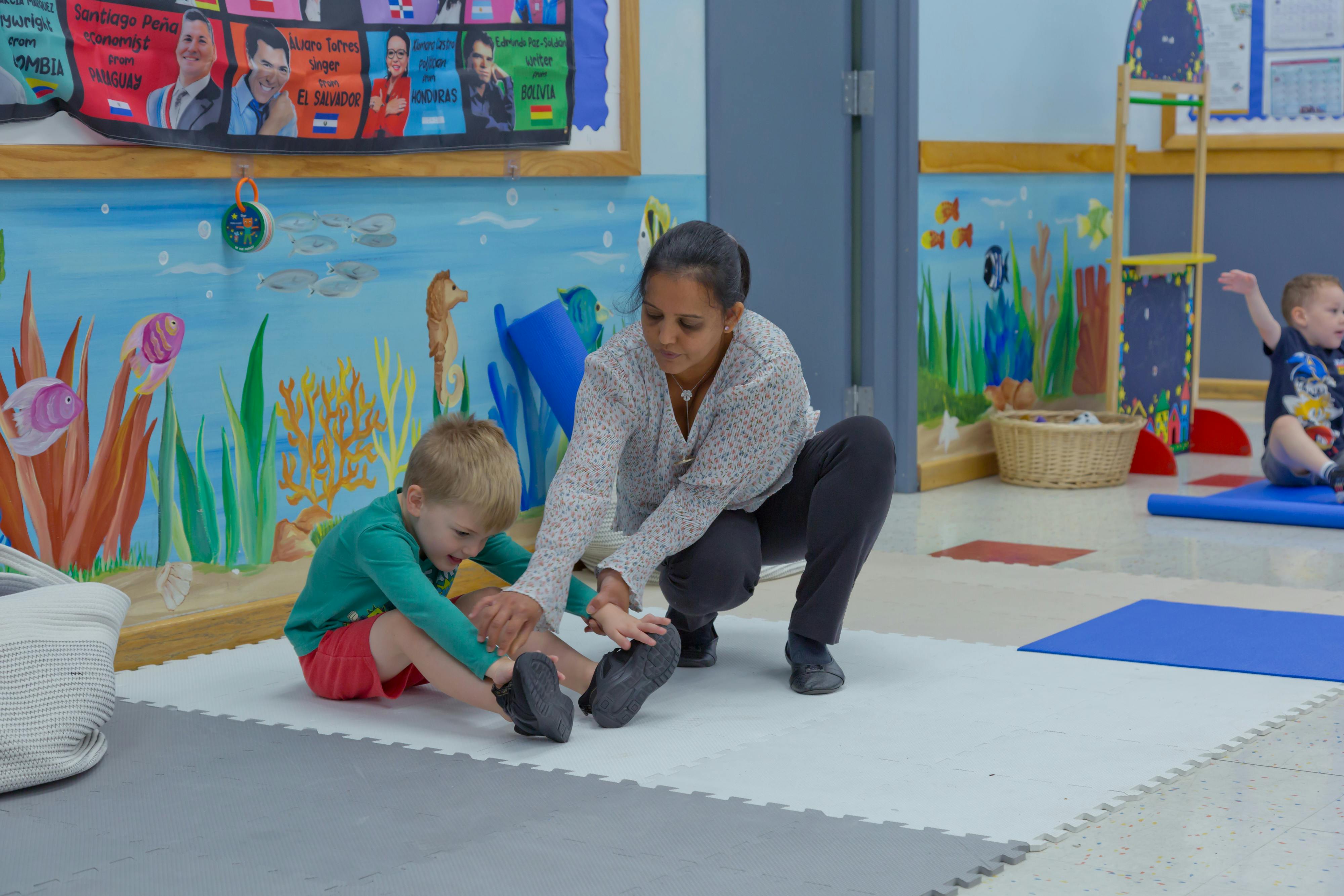 Adult and child stretching on a mat in a classroom