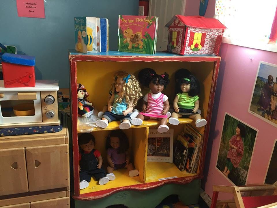 Dolls sitting on shelves in a toy house