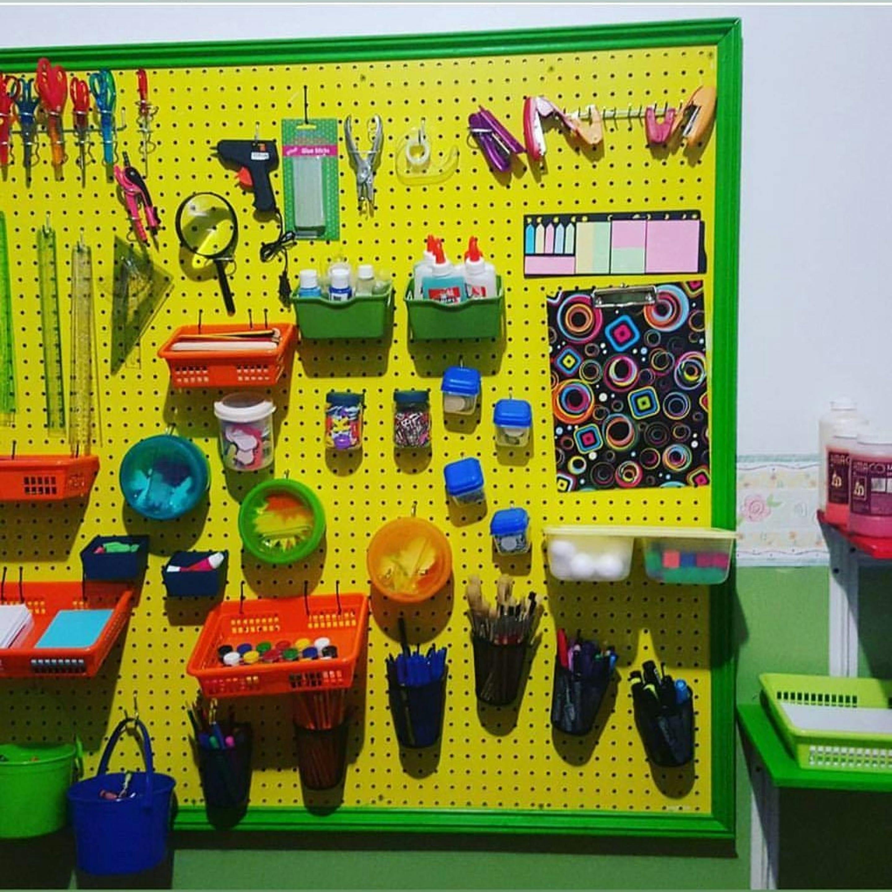 Yellow pegboard with various craft supplies and tools organized in containers