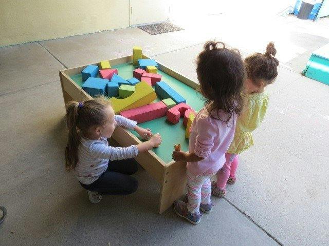 Three children playing with colorful blocks on a table