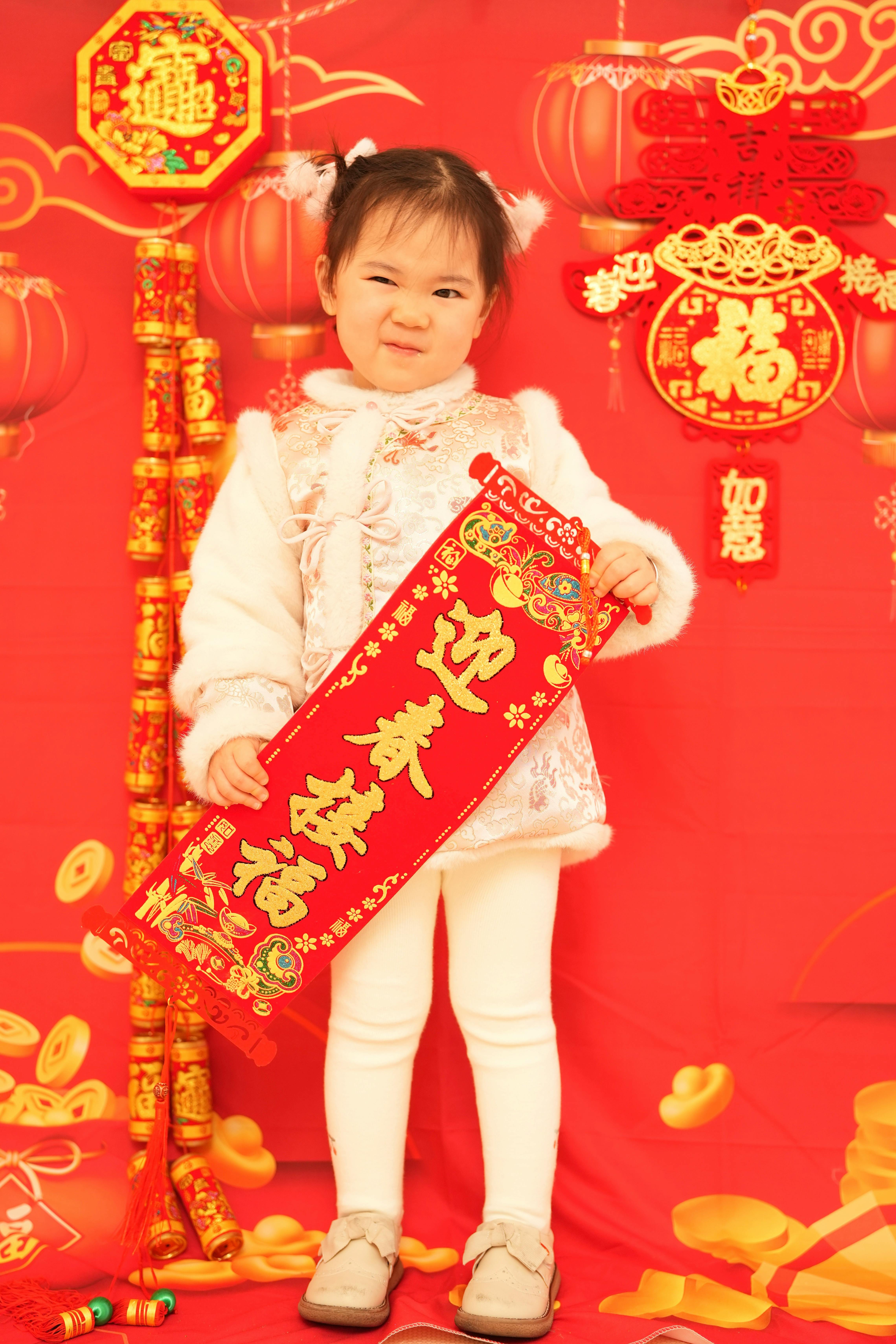 Child in traditional clothing holding a red scroll for Chinese New Year