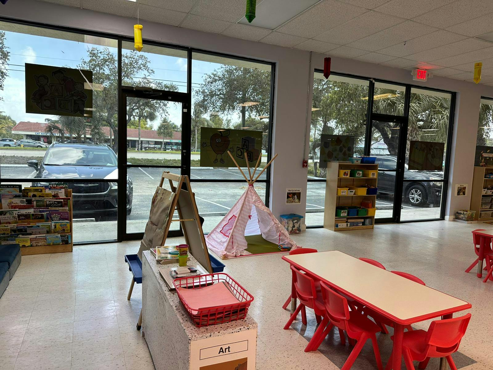 Classroom with small tables and chairs, play tent, and large windows