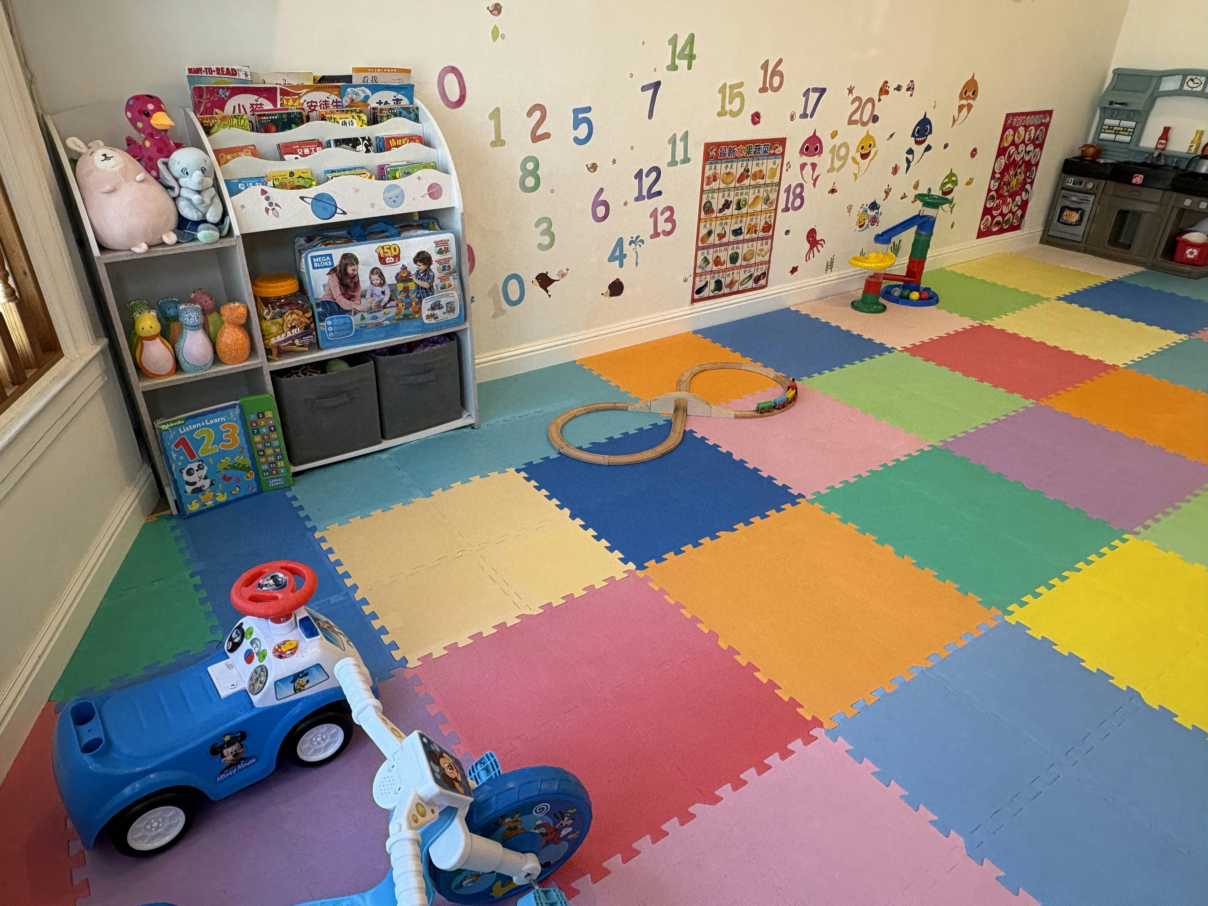 Playroom with colorful floor mats, toys, and number decals on the wall