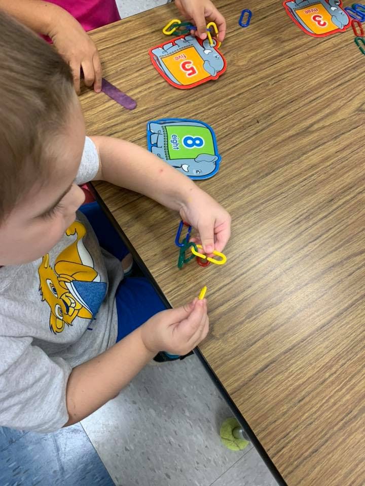 Child playing with colorful linking chains and number cards on a table