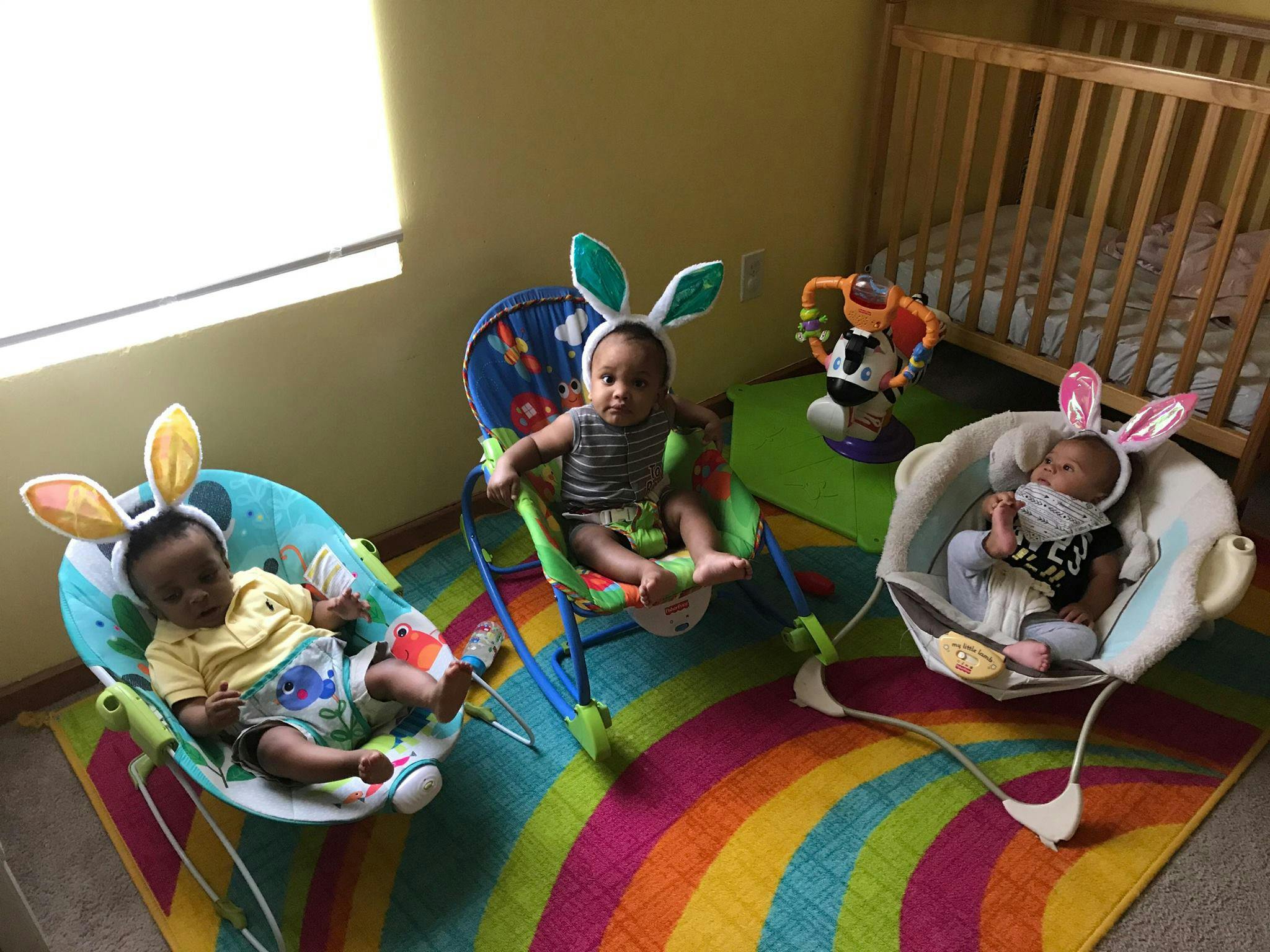 Three babies wearing bunny ears in bouncer seats