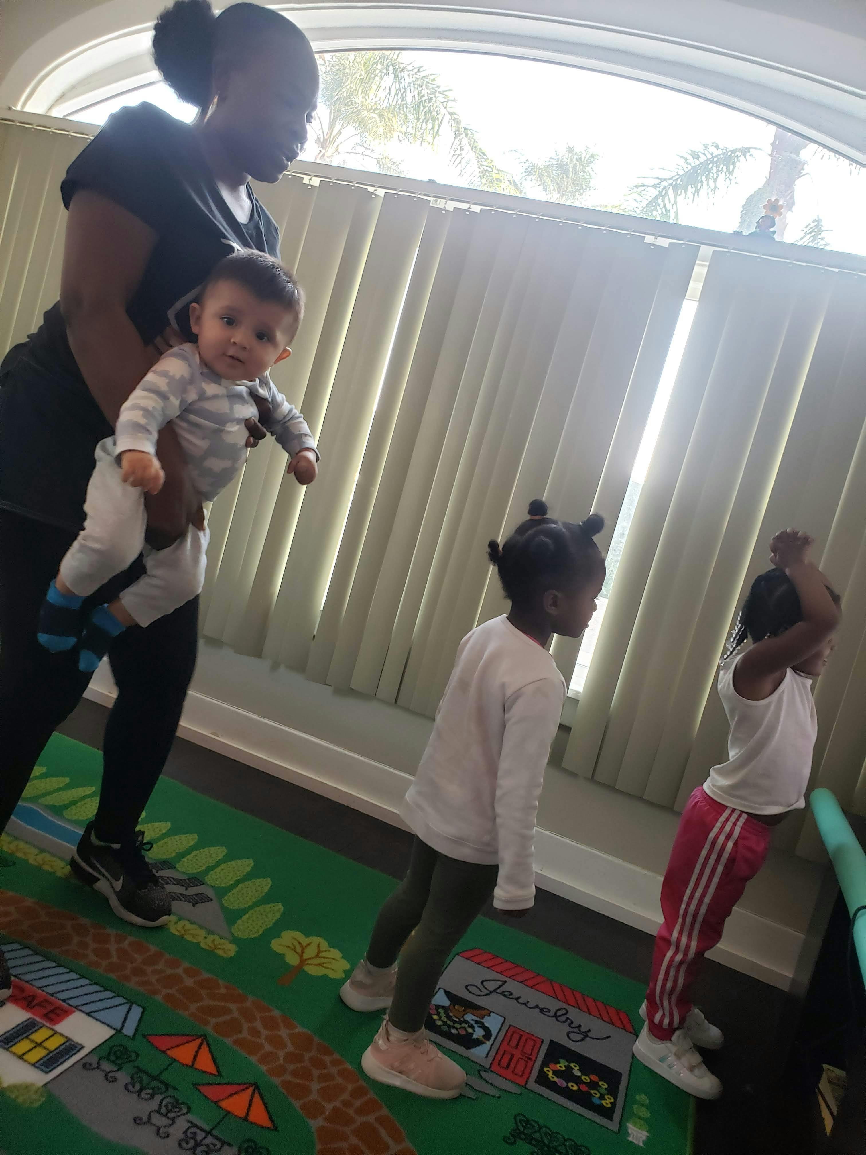 Person holding a baby, with two children standing nearby