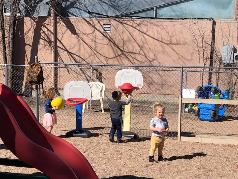 Children playing with basketball hoops on a sandy playground
