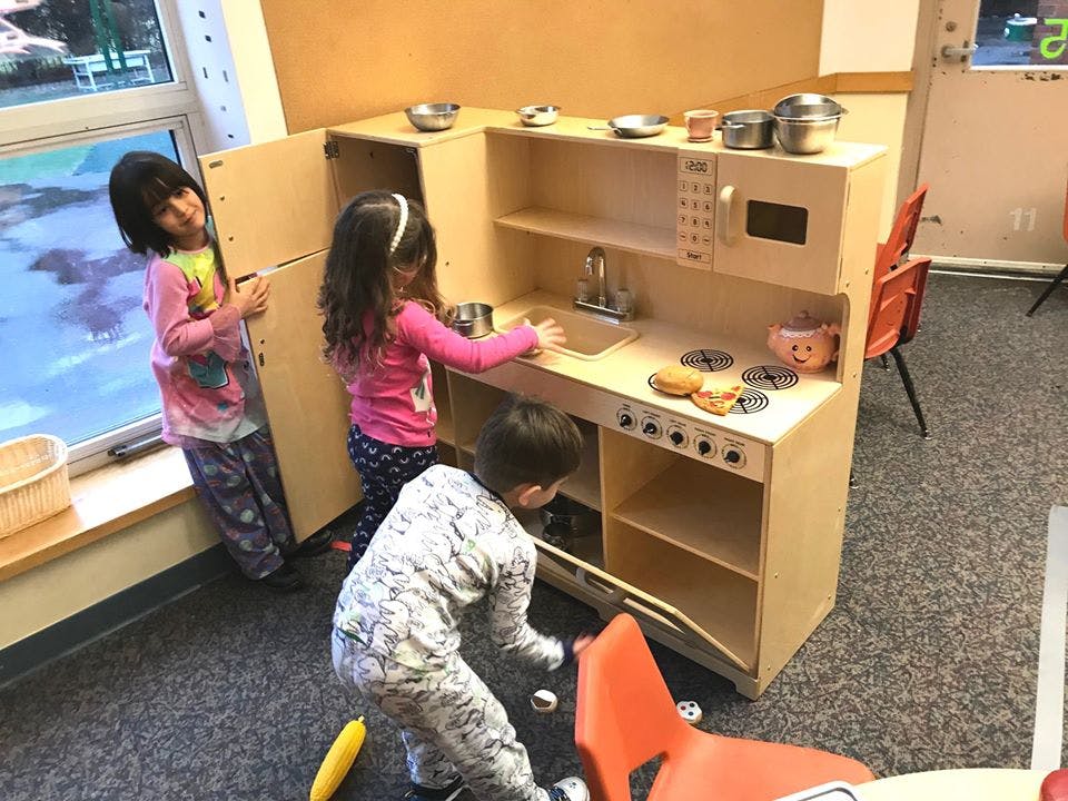Three children playing with a toy kitchen set