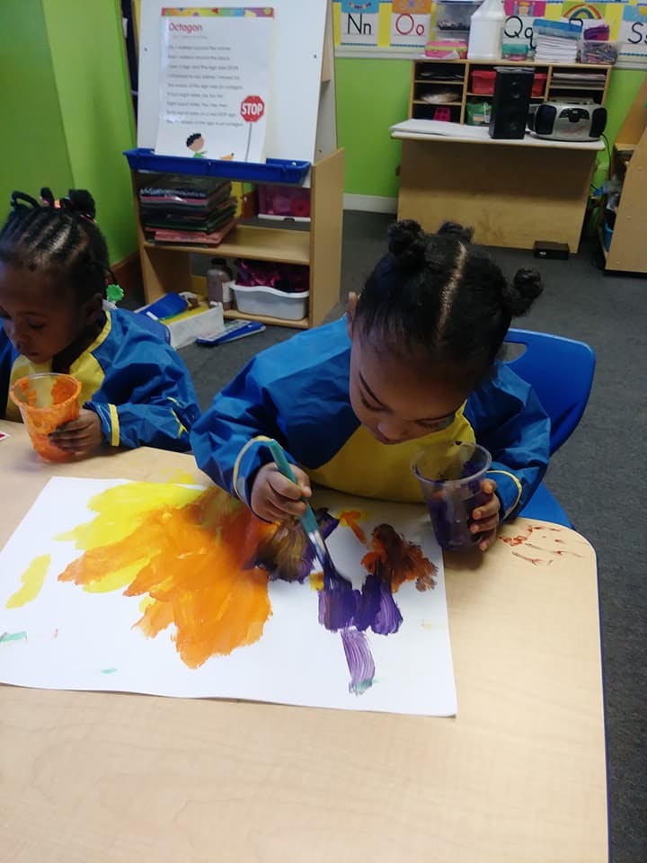 Two children painting at a table in a classroom
