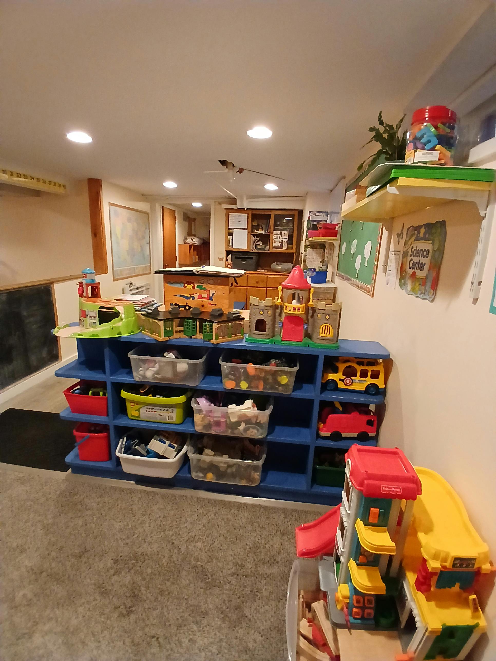 Blue shelving unit with clear bins of toys and other play items