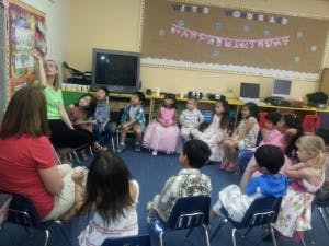 Adult leading a group of children sitting in a circle in a classroom