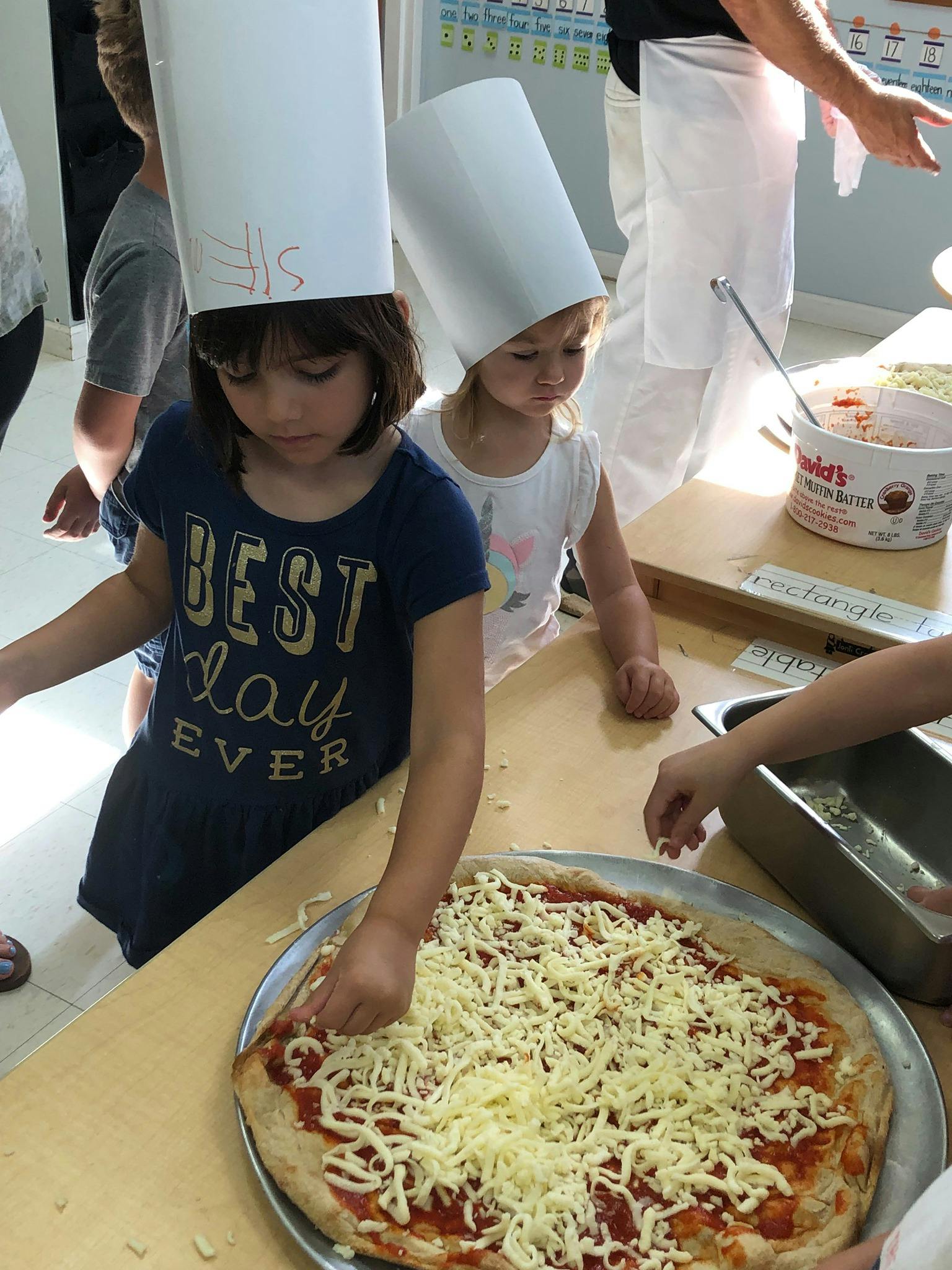 Child in chef hat making pizza