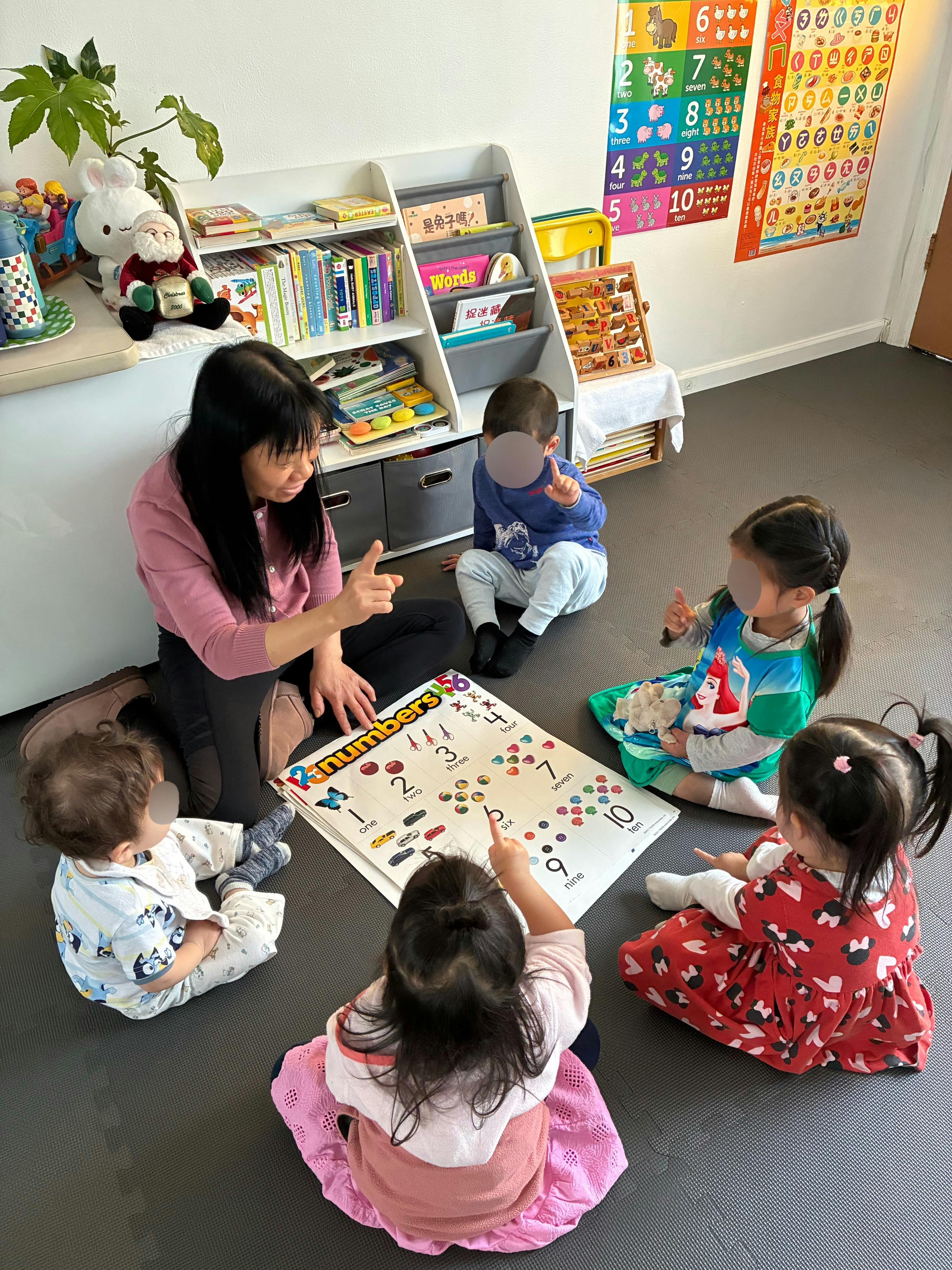 Adult and four children sitting on the floor around a "123 numbers" learning mat