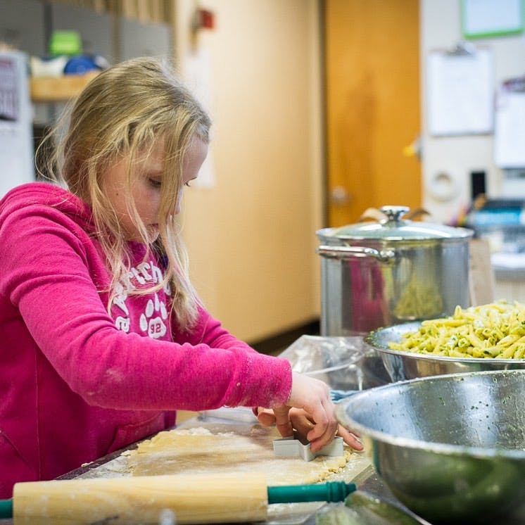 Child cutting dough with a cookie cutter in a kitchen