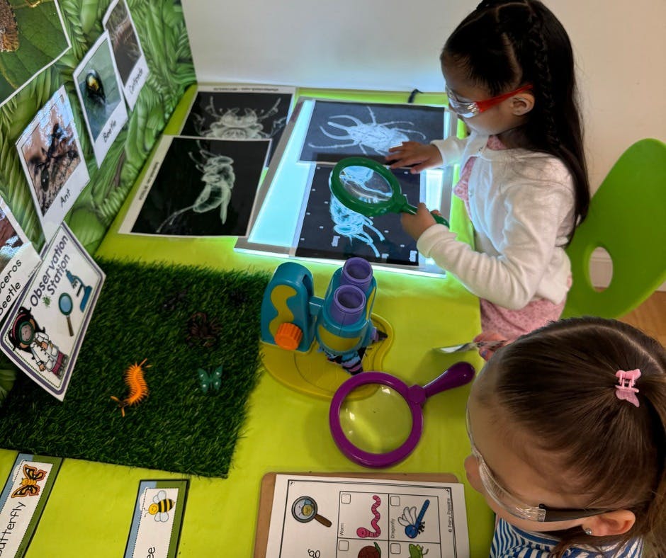 Child holding a magnifying glass over an insect image on a light table