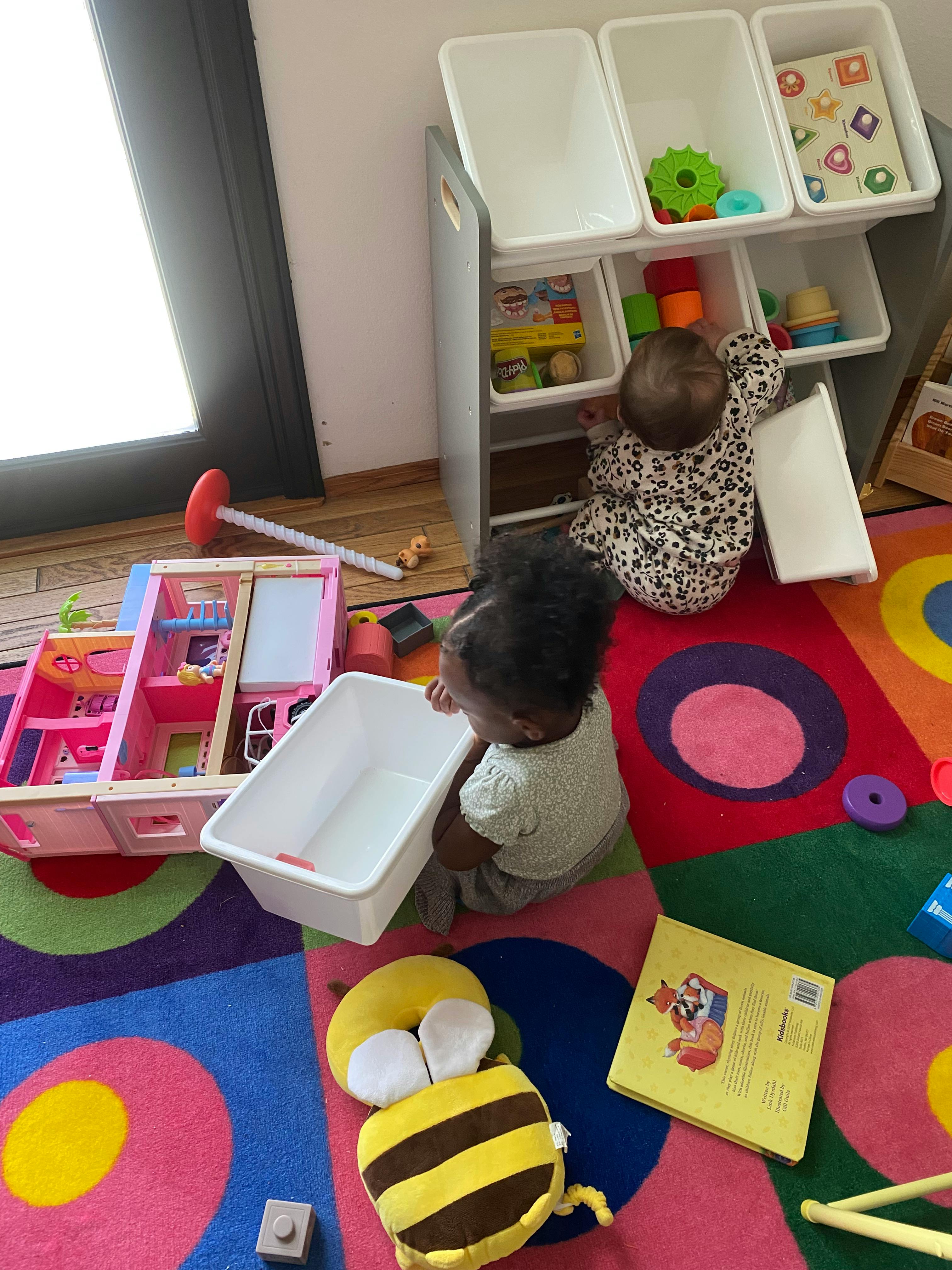 Two children playing with toys on a colorful rug, one child in leopard print