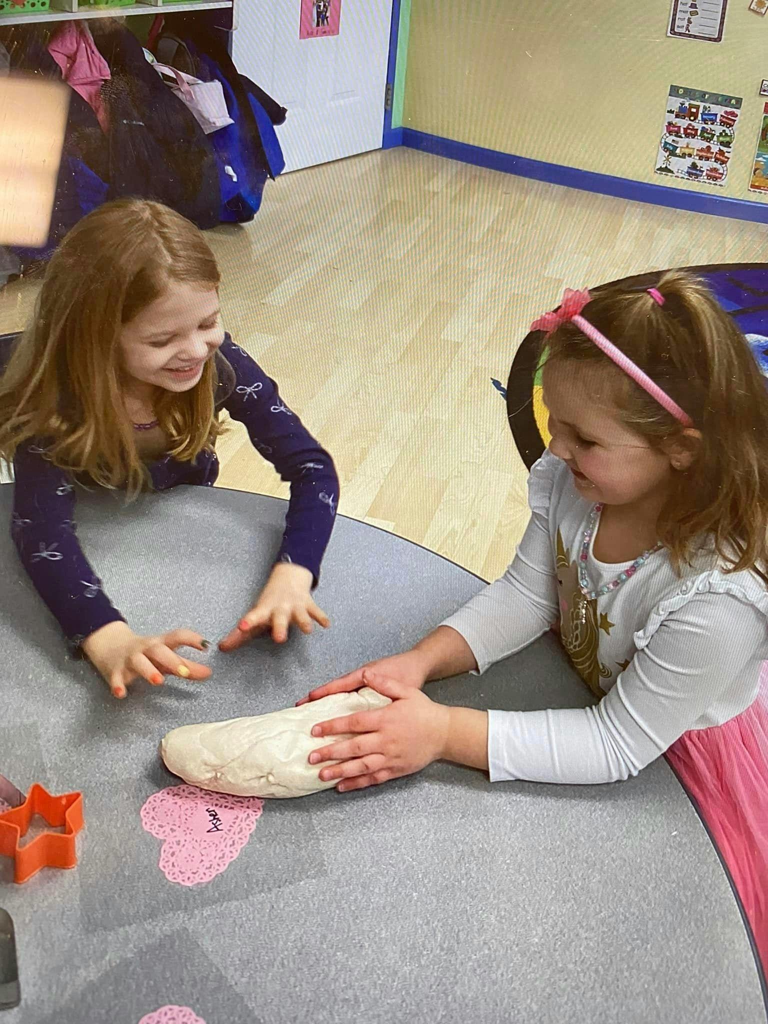 Two children playing with dough on a table