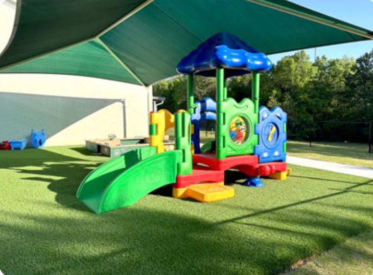 Colorful playground structure with a slide on artificial turf
