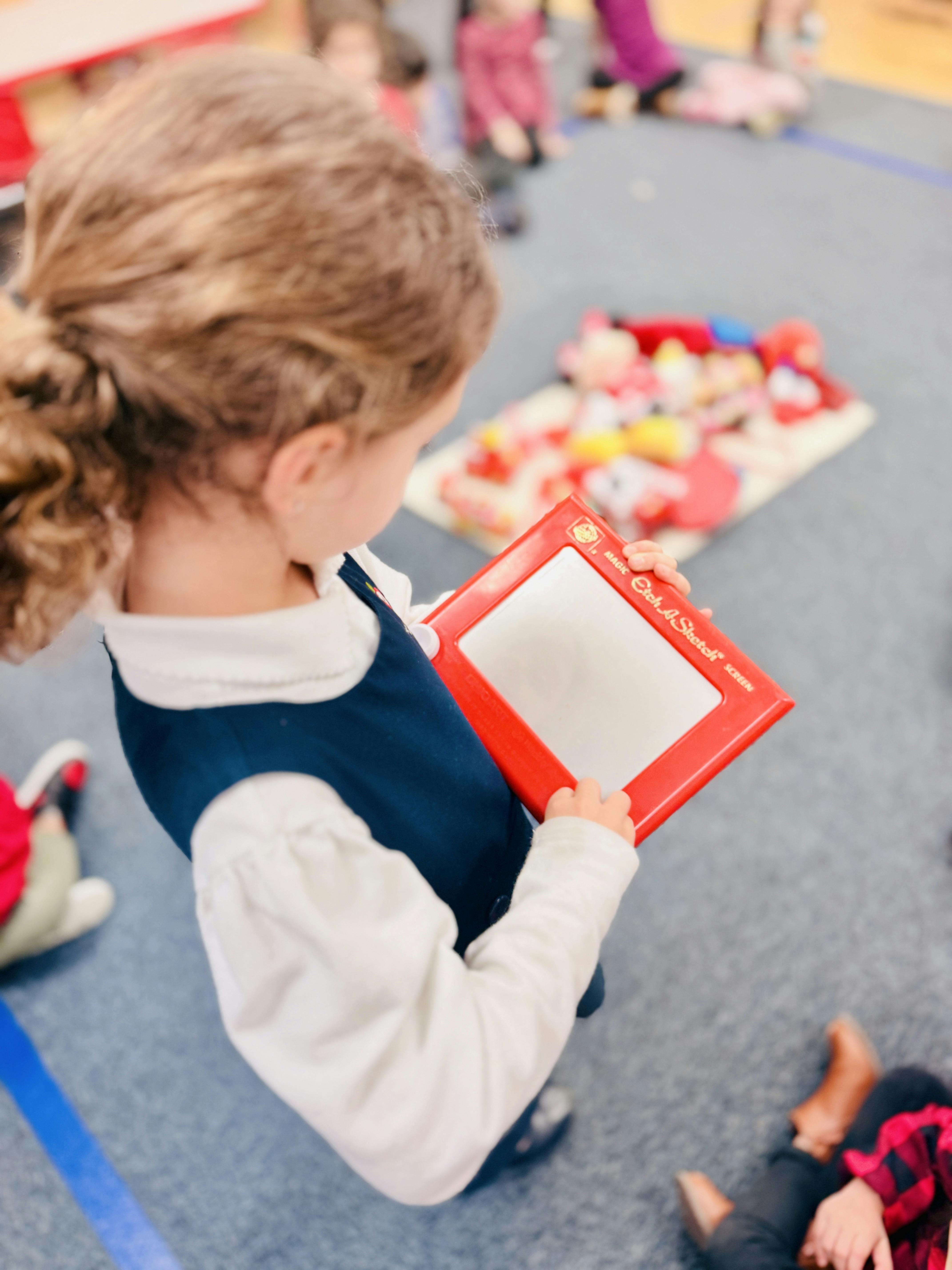 Child holding an Etch A Sketch toy