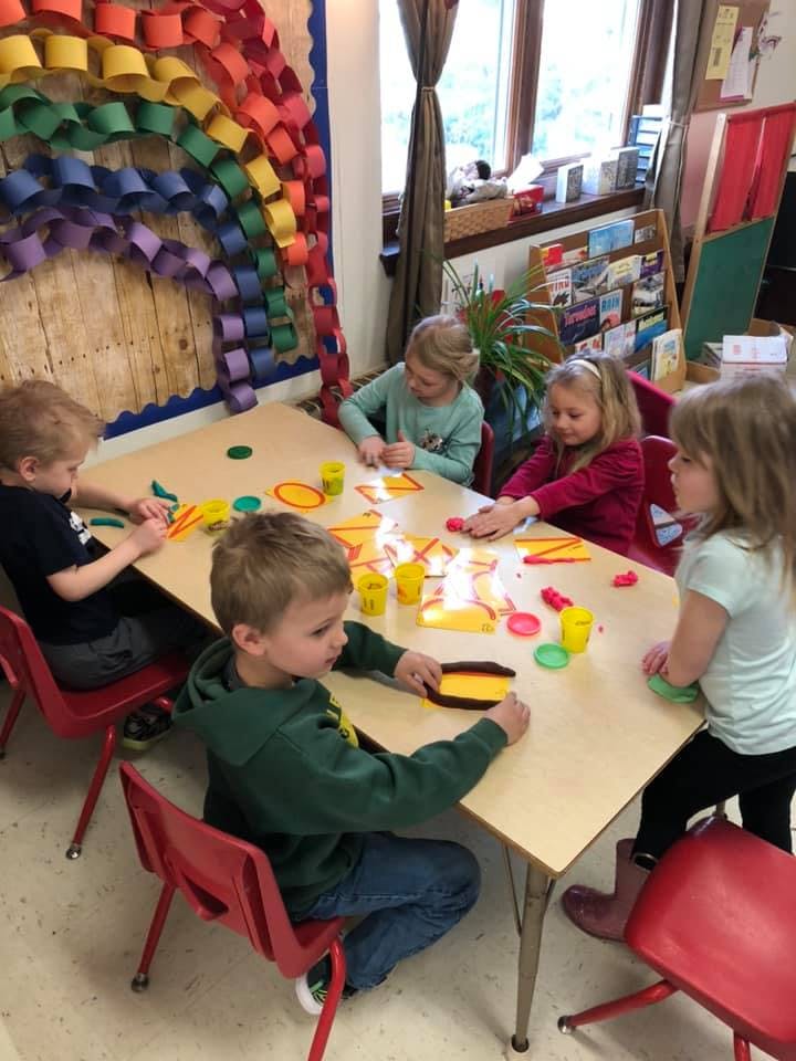 Children sitting at a table playing with modeling clay